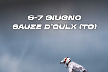 Ciclista di enduro che salta su una superficie rocciosa e sullo sfondo le montagne ed il cielo grigio 